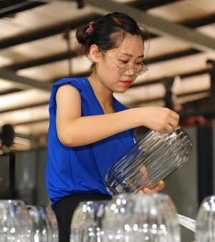 A glass vase inspector is examining the surface of the vase