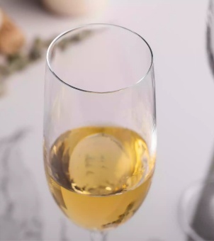 A close-up of the cold-cut rim of a champagne glass, showcasing the smooth rim and the golden champagne inside.