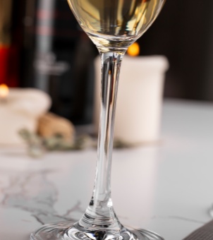 A close-up of the slender stem of a crystal champagne glass showcases its one-piece molding process and lustrous finish.