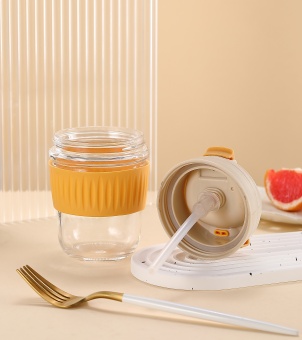 Xinghuo Glass travel mug, showing the disassembled BPA-free food-grade straw lid and yellow heat-resistant silicone sleeve