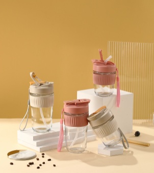 This display showcases several Xinghuo Glass portable coffee cups in different colors and with carrying straps.