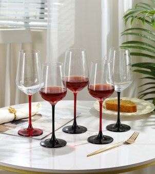 The Xinghuo Glass set of custom-made black and red crystal wine glasses with stems is placed on the dining table.