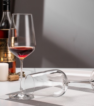The Xinghuo Glass showcases crystal wine glasses shaped like a wine glass bowl; one stands upright holding wine, while the other lies horizontally on the table.
