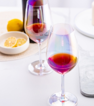Two Xinghuo Glass crystal wine glasses filled with red wine on a white dining table