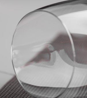 A close-up macro view of a horizontally placed Xinghuo Glass crystal wine glass showcases the smooth, un-rolled, laser-cut rim.