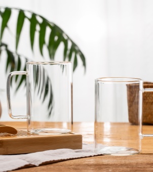 Two flawless Xinghuo Glass empty mugs are placed on a wooden tea tray and table.