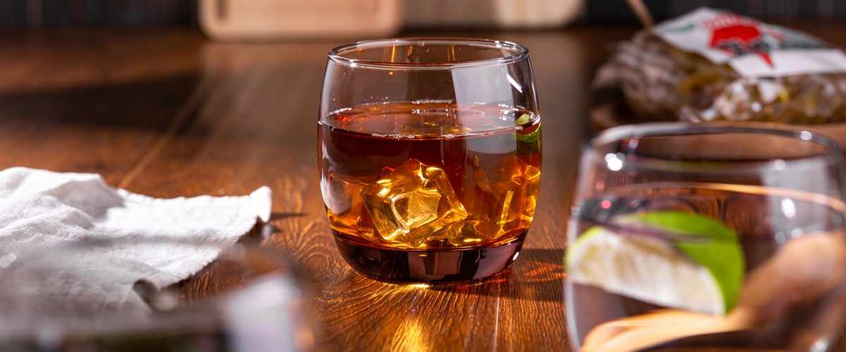 Clear stemless wine glass with an iced drink on a wooden bar table