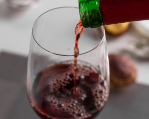 Close-up image of red wine being poured into a crystal goblet.