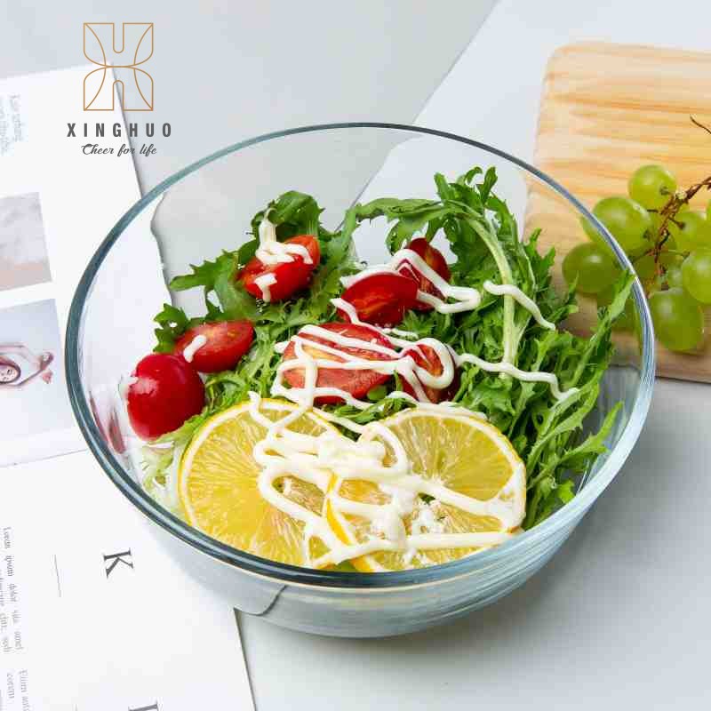 A top-down view of a high-transparency glass bowl containing a lemon and vegetable salad.
