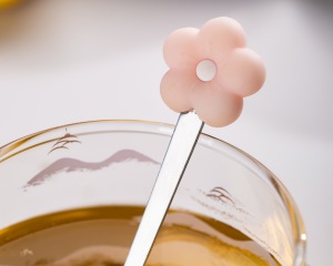 Close-up image of the pink flower-shaped stainless steel stirring spoon that comes with the Xinghuo glass.