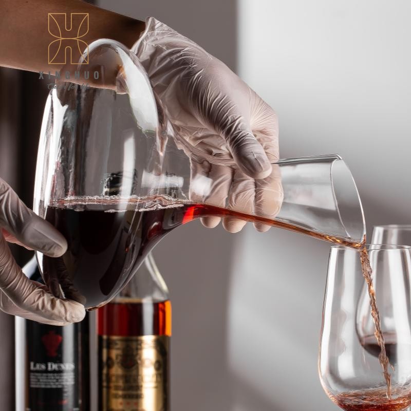 A sommelier elegantly pours red wine using a crystal decanter.