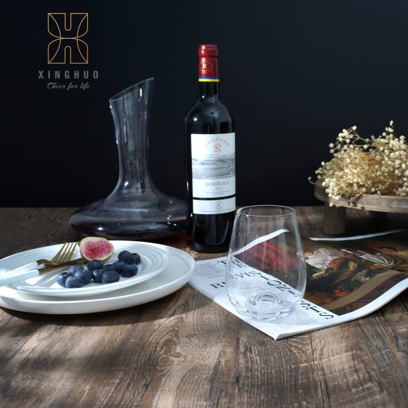 A scene depicting a stemless crystal glass paired with a wine bottle and decanter.