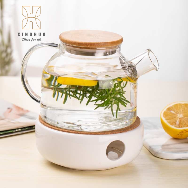 Image of a glass teapot for heating water plants in a white porcelain warmer.