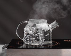 Image of a high borosilicate heat-resistant glass teapot steaming on an electric ceramic hob.