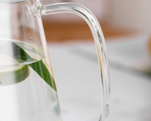 Macro close-up image of the ergonomic handle of a heat-resistant glass water pitcher.