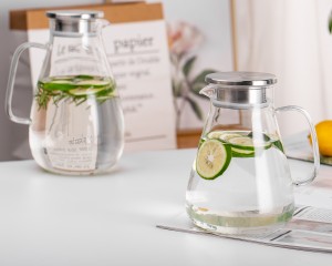 Two borosilicate glass water jugs filled with lime-infused water and fresh herbs on a white table