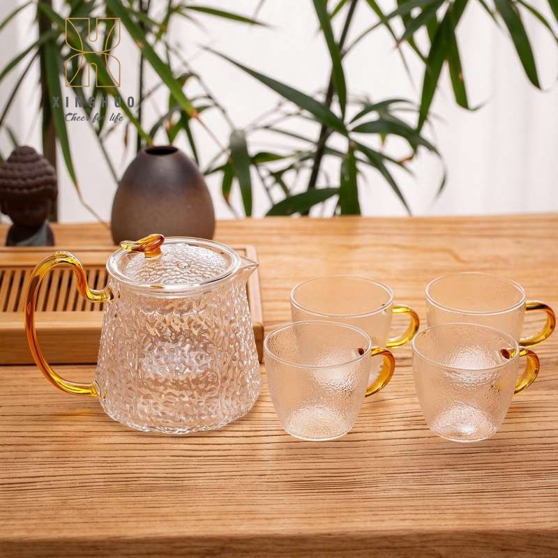 Images of a hammered heat-resistant glass teapot and a four-cup set displayed on a xinghuo glass tea tray.